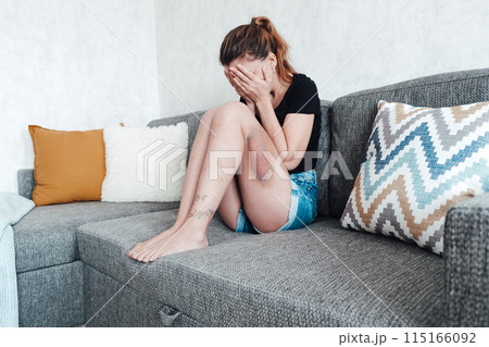 A young woman with a bruise on her hip is on the sofa with her face covered A young woman with a bruise on her hip is on the sofa with her face covered 115166092