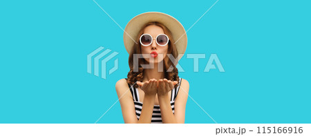 Portrait of beautiful young woman posing blowing kiss wearing summer straw hat on blue background Portrait of beautiful young woman posing blowing kiss wearing summer straw hat on blue background 115166916