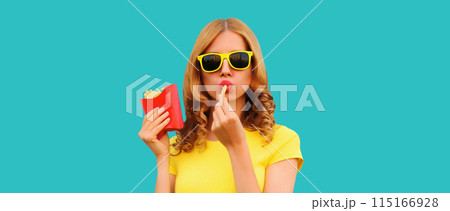 Portrait of stylish young woman eating french fries, fried potatoes fast food Portrait of stylish young woman eating french fries, fried potatoes fast food 115166928