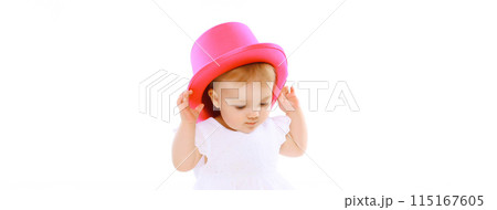 Cheerful baby playing with pink hat on the floor on white studio background Cheerful baby playing with pink hat on the floor on white studio background 115167605