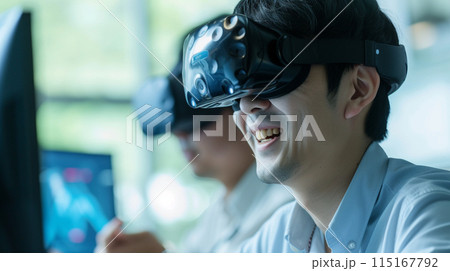 職場で仮想現実シミュレーターを調べている同僚を見つめる笑顔の日本人エンジニア 職場で仮想現実シミュレーターを調べている同僚を見つめる笑顔の日本人エンジニア 115167792