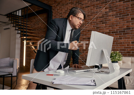 Mad businessman screaming on computer having online meeting at home office 115167861