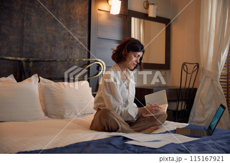 Busy young businesswoman working online from hotel room 115167921