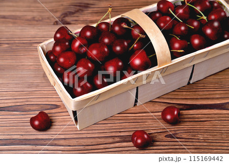 Ripe natural cherries, sweet cherries in a birch bark basket on a wooden background, close-up 115169442