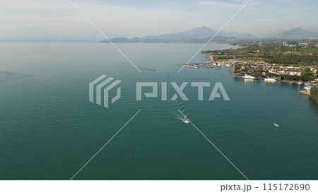 Beautiful panoramic drone view of Lake Garda. High top view of water landscape with hills of mountains and city on sunny summer day. Peschiera del Garda, Italy 115172690