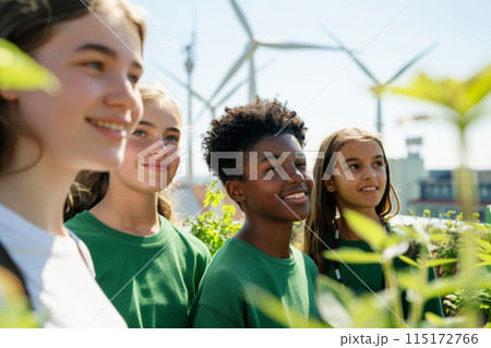 Group of kids in green tops standing outdoors against a backdrop of wind turbines, embodying teamwork and commitment to sustainability and renewable energy. Group of kids in green tops standing outdoors against a backdrop of wind turbines, embodying teamwork and commitment to sustainability and renewable energy. 115172766