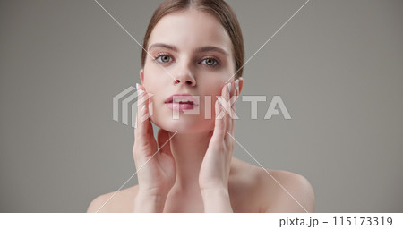 Beauty, health, cosmetics, anti-aging therapy and skin care concept - young beautiful brunette Caucasian woman posing and looking at the camera with a calm confident look like in a mirror Beauty, health, cosmetics, anti-aging therapy and skin care concept - young beautiful brunette Caucasian woman posing and looking at the camera with a calm confident look like in a mirror 115173319