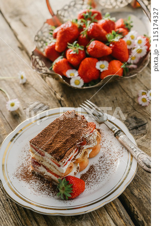 strawberry tiramisu served on a white plate and wooden background, decorated with flowers, Italian tiramisu dessert 115174327