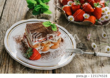 strawberry tiramisu served on a white plate and wooden background, decorated with flowers, Italian tiramisu dessert 115174328