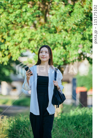 スマホを操作しながら歩く若い女性 スマホを操作しながら歩く若い女性 115175102