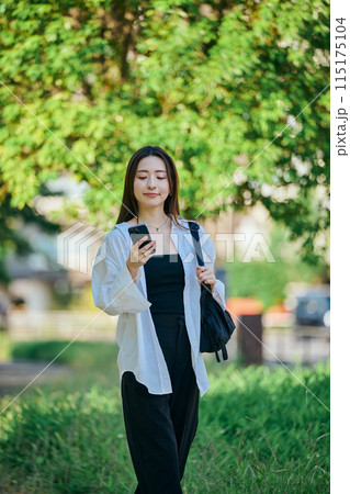 スマホを操作しながら歩く若い女性 115175104