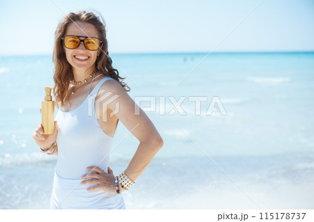 smiling modern woman on seashore with spf 115178737