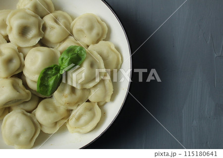 Cooked boiled dumplings in a bowl of basil greens top view close-up on a gray background with space for text copyspace Cooked boiled dumplings in a bowl of basil greens top view close-up on a gray background with space for text copyspace 115180641