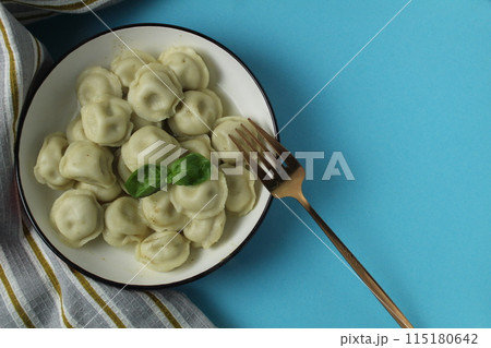 Table setting dumplings in a bowl with fork, napkin and herbs basil top view on a blue background with space for text copyspace Table setting dumplings in a bowl with fork, napkin and herbs basil top view on a blue background with space for text copyspace 115180642