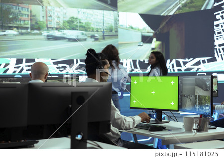 Indian employee operates on mockup display next to CCTV real time video, monitoring couriers activity through urban traffic via public surveillance system. Dispatcher in control center. 115181025