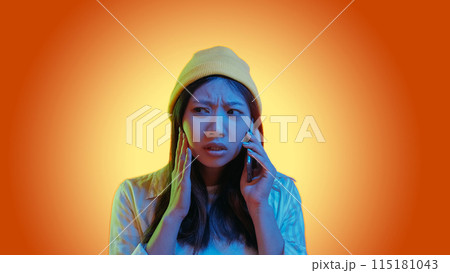 Disturbing call. Mobile scam. Blue color neon light scared confused woman speaking on phone isolated on orange gradient empty space background. 115181043