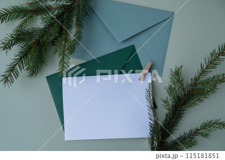 Green background with Christmas tree branch decor and copy space mock up white envelope. Template for Christmas greeting card New Year postcard. Flat lay 115181851