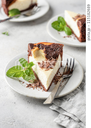 Piece of homemade chocolate cheesecake topped with chocolate chips mint leave on a plate on white textured background Piece of homemade chocolate cheesecake topped with chocolate chips mint leave on a plate on white textured background 115182689