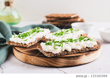 Homemade crispy rye toasts with ricotta and herbs on a board 115183369