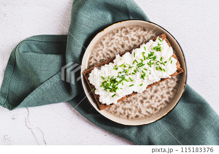 Close up of homemade crispy rye toast with ricotta and herbs on a board top view Close up of homemade crispy rye toast with ricotta and herbs on a board top view 115183376