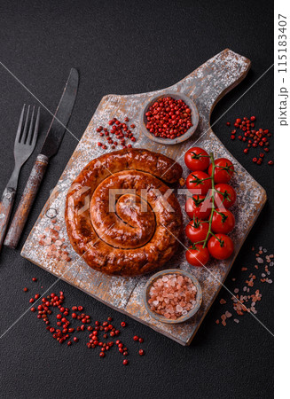 Delicious homemade sausage in the form of a spiral baked on the grill with salt, spices Delicious homemade sausage in the form of a spiral baked on the grill with salt, spices 115183407