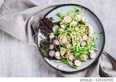 Close up of fresh vitamin salad of cucumber and radish on a plate on the table top view Close up of fresh vitamin salad of cucumber and radish on a plate on the table top view 115183408