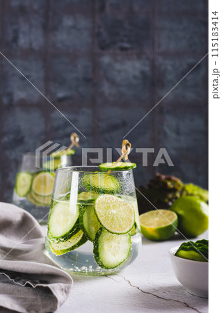 Refreshing carbonated lemonade with lime and cucumber in glasses on the table vertical view 115183414