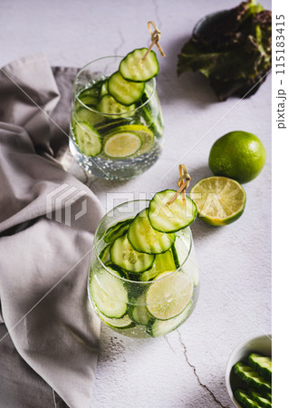 Detox cocktail with cucumber and lime in glasses on the table vertical view 115183415