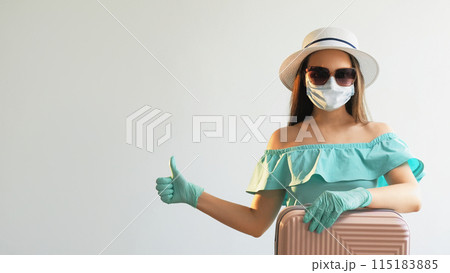 Pandemic journey. Girl recommending. Woman in medical mask gloves summer dress with suitcase approving thumbs up at empty space isolated on white background. 115183885
