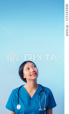 Curious doctor. Medical advertising. Cheerful smiling physician woman in uniform with stethoscope looking up isolated on blue empty space background. 115183886