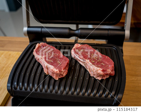 Raw fillet beef meat for steaks on the home electric grill Raw fillet beef meat for steaks on the home electric grill 115184317