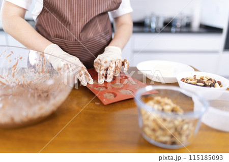 A woman is making cookies on a wooden table 115185093