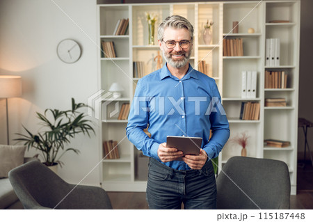 Man psychologist wearing blue shirt holding clipboard standing in his office 115187448
