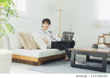 リビングでパソコンを見る若い男性 115188250
