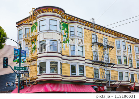 Bay windows and escape ladders on yellow building with restaurant awning below apartments Bay windows and escape ladders on yellow building with restaurant awning below apartments 115190031