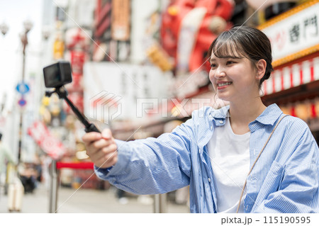 都会の繁華街で自撮り撮影をする若くて可愛い女性｜大阪観光イメージ｜大阪府大阪市道頓堀商店街 115190595