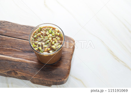 Spring Onion Coffee Or Scallion Coffee on Wooden Tray. Popular Beverage In China. Top View Glass Of Drink, Cappuccino Or Latte With Onions On Granite Table. Copy Space. Horizontal Plane. 115191069