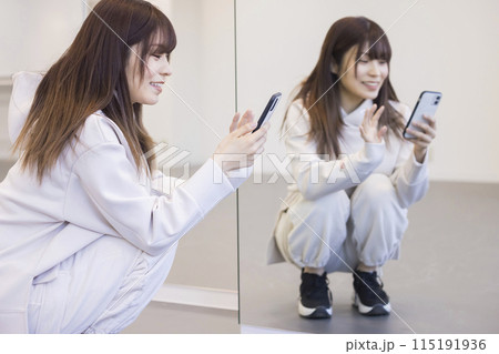 ダンススタジオの鏡の前でスマホを見る若い女性 115191936