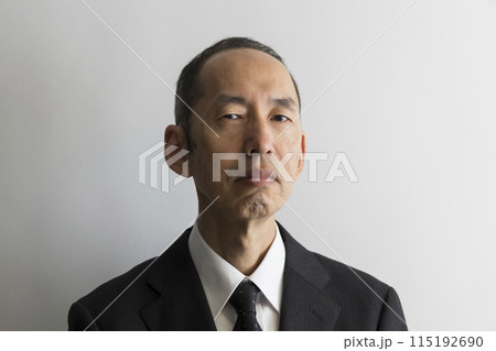 睨むスーツ姿の日本人の中年男性のポートレイト 睨むスーツ姿の日本人の中年男性のポートレイト 115192690