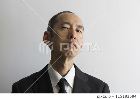 上から目線で睨むスーツ姿の日本人の中年男性のポートレイト 上から目線で睨むスーツ姿の日本人の中年男性のポートレイト 115192694