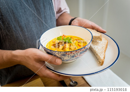 A bowl of pumpkin porridge with tofu and vegetables 115193018