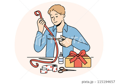 Man makes gift with own hands decorating box with red ribbon with festive paper. 115194657