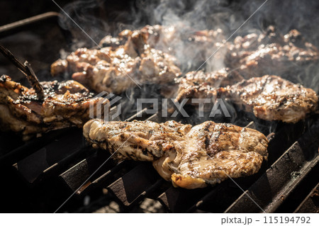 High angle of appetizing and delicious meat pieces with smokes placed on barbecue grill in dark restaurant kitchen in daylight High angle of appetizing and delicious meat pieces with smokes placed on barbecue grill in dark restaurant kitchen in daylight 115194792