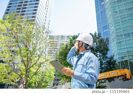 作業服の男性　オフィスビル　見上げる　指差し 115195665