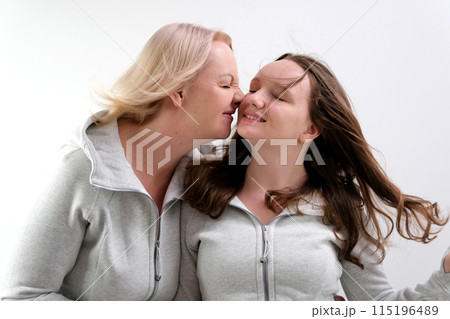 Adorable lovely fun satisfied elder parent mom with young adult daughter two women together wearing casual clothes hugging cuddle close eyes isolated on plain blue cyan background. Family day concept Adorable lovely fun satisfied elder parent mom with young adult daughter two women together wearing casual clothes hugging cuddle close eyes isolated on plain blue cyan background. Family day concept 115196489