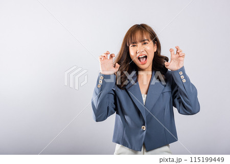 Asian happy portrait beautiful business young woman wearing a suit angry and mad raising fist frustrated and furious while shouting with anger isolated, studio shot on white background and copy space 115199449