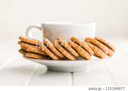 Chocolate Filled Cookies on a Saucer Beside a Cup Chocolate Filled Cookies on a Saucer Beside a Cup 115199977