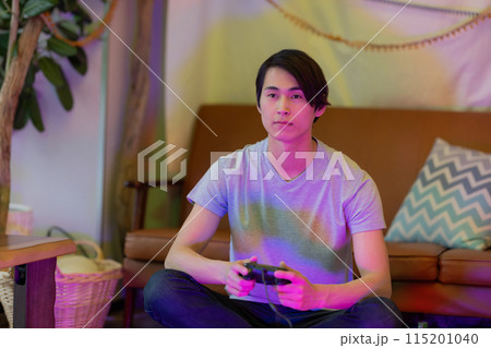 夜のリビングでゲームをする若い男性 夜のリビングでゲームをする若い男性 115201040