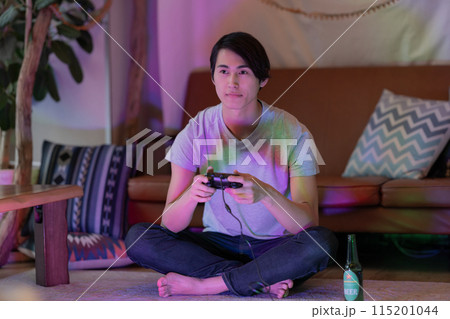 夜のリビングでゲームをする若い男性 夜のリビングでゲームをする若い男性 115201044