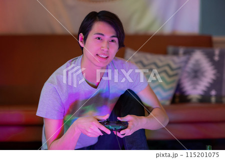 夜のリビングでゲームをする若い男性 115201075